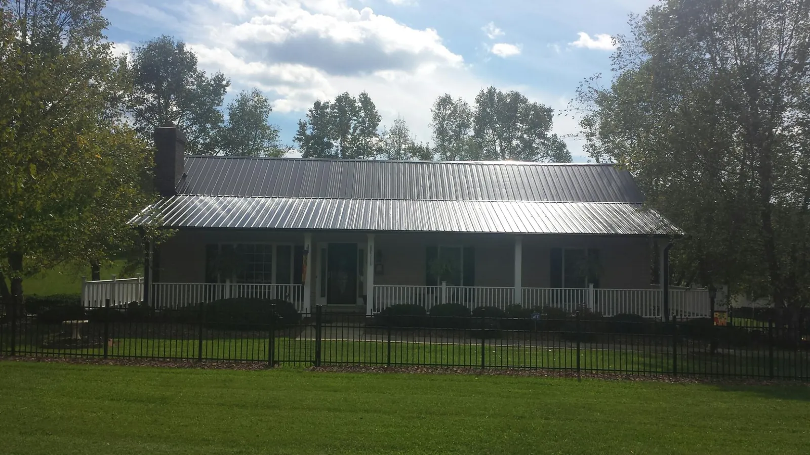 Gray metal roof on a brick ranch with a full width front porch — Gutter Guard Installation work by our crew in Mendota